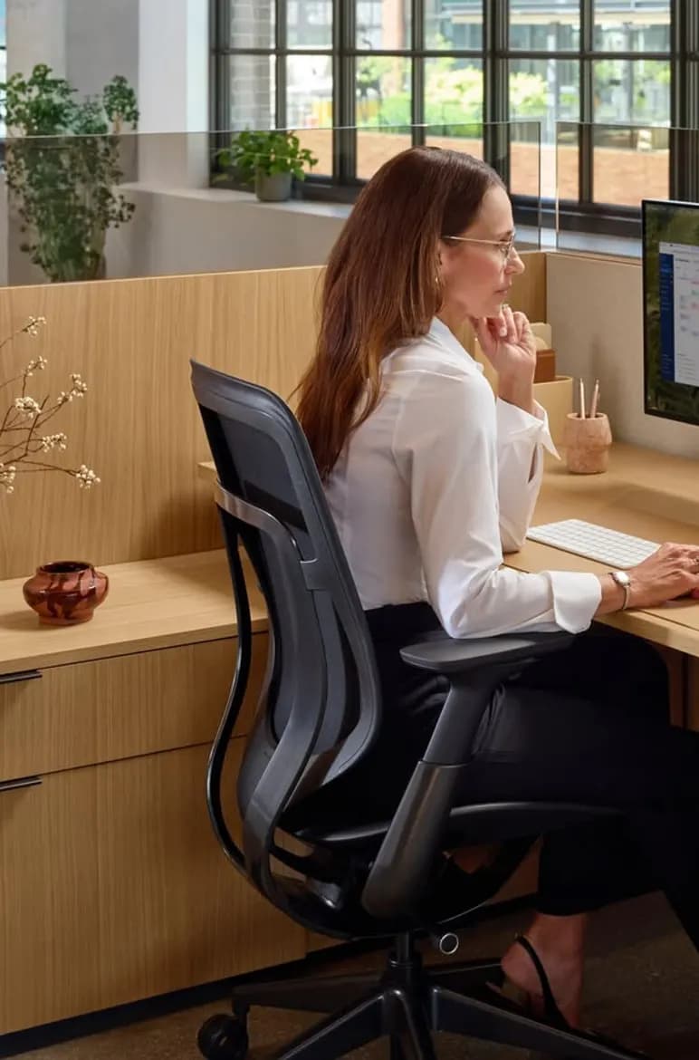 An analyst reviewing research on a workstation display in a bright office