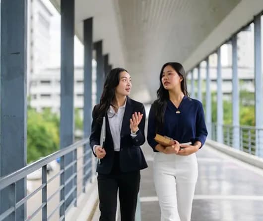 Two colleagues talking while walking through a corridor