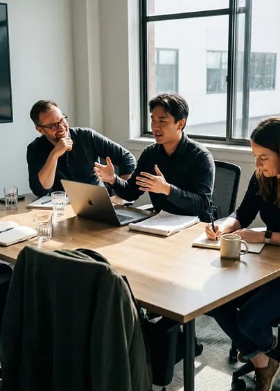 Three colleagues discussing work around a table