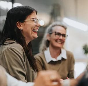 Two colleagues laughing together during a meeting