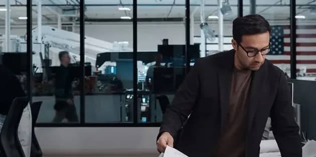 Professional reviewing a printed page in a glass-walled engineering studio