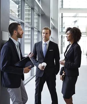 Three colleagues talking in a bright office corridor