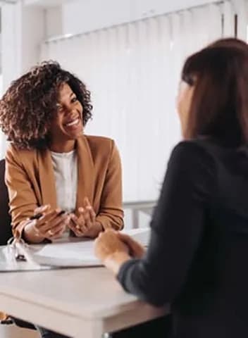 Two colleagues talking across a table in a bright office