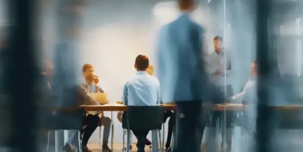 A team meeting around a table seen through blurred glass