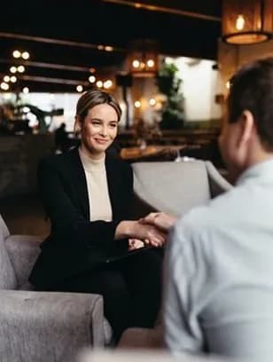 A professional shaking hands with a client in a lounge