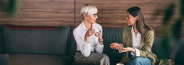 Two colleagues chatting over coffee on a sofa