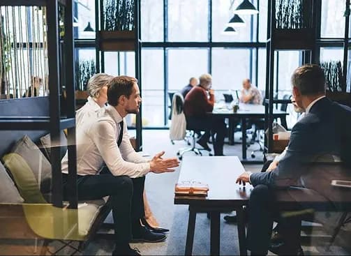 Business people meeting at a table in a busy open-plan office