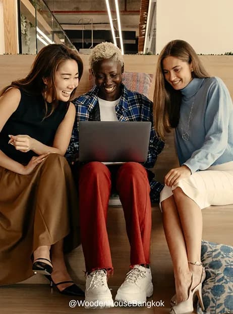 Three friends laughing together over a laptop