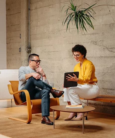 Two colleagues reviewing a tablet together in a lounge