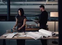 Two people reviewing plans on a table in a dim studio
