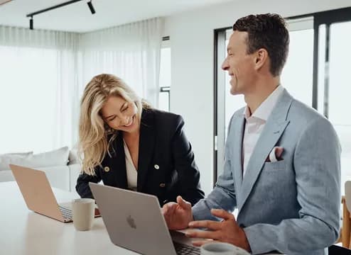 Two colleagues talking over a laptop in an office