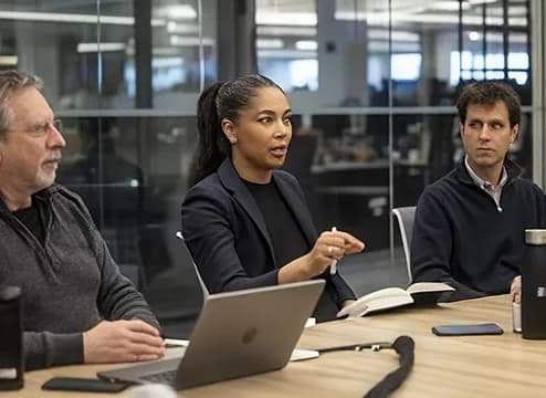 Three colleagues reviewing updates together at a desk