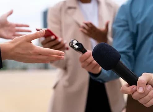 Journalist holding a microphone toward an interviewee