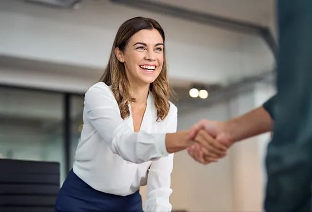 Colleague smiling while shaking hands in an office