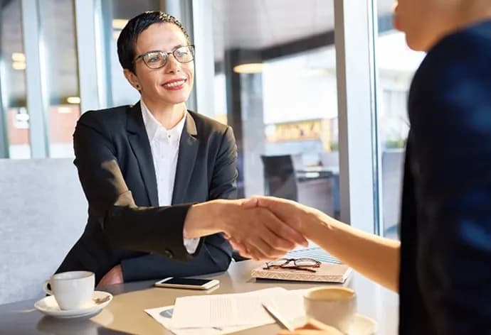 Two colleagues shaking hands across a café table