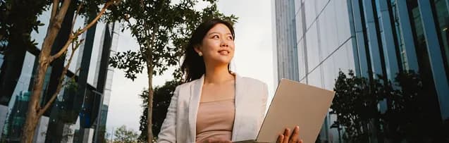 Analyst walking outside an office building with a laptop