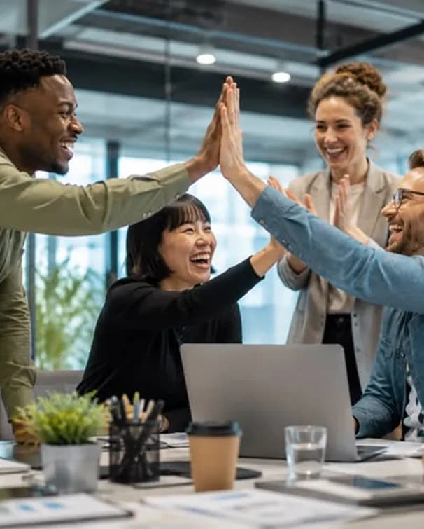 Team celebrating together around a desk in an office