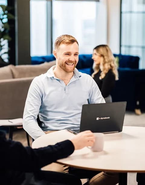 Colleague smiling while working on a laptop in a bright office