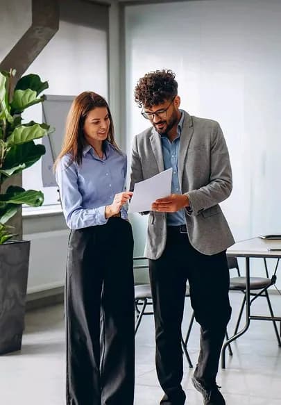 Two colleagues reviewing a document while standing in an office