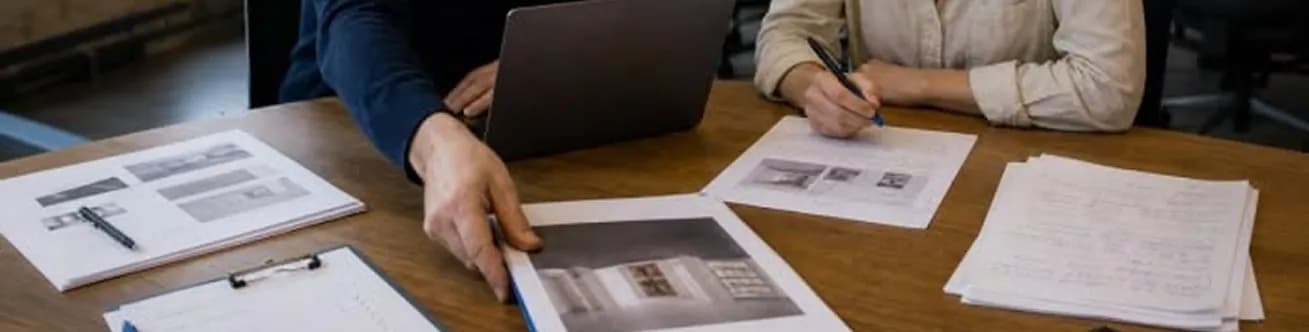 Two analysts reviewing printed source documents at a table