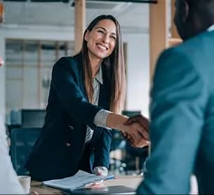 A smiling professional shaking hands across a desk