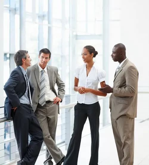 Four colleagues talking together in a bright office atrium