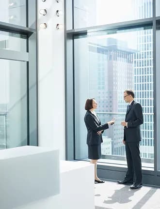 Two colleagues talking beside a floor-to-ceiling office window