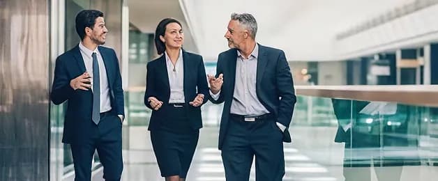 Three colleagues talking while walking through an office