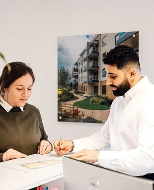 An adviser and a client reviewing documents together at a desk