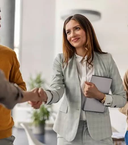 A smiling professional shaking hands with a colleague in a bright office