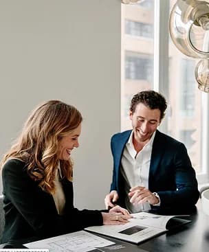 Two colleagues laughing while reviewing a document together