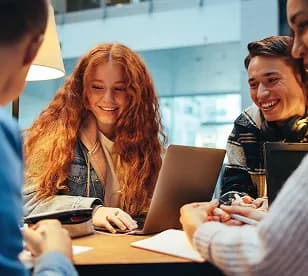 Young colleagues smiling while working together at a laptop