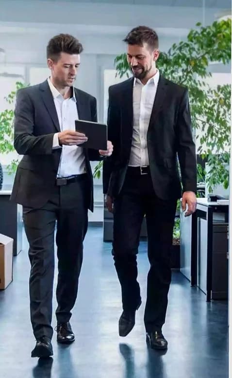 Two colleagues walking through an office reviewing a tablet