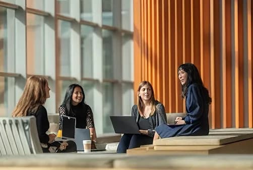 Colleagues talking with laptops in a sunlit atrium