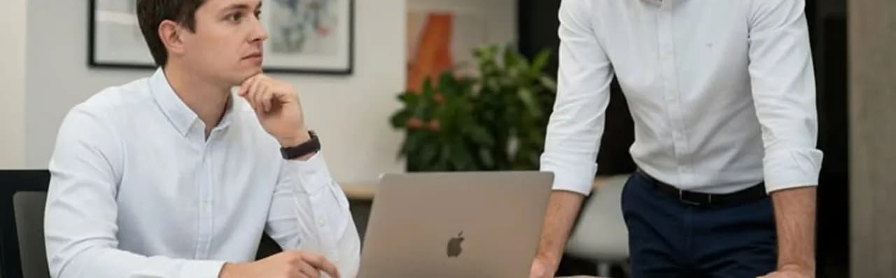 Two colleagues reviewing work together on a laptop