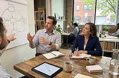 Colleagues talking around a table in front of a whiteboard