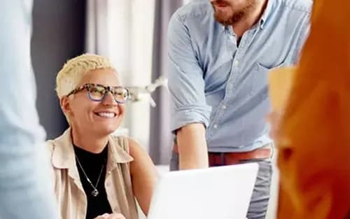 A smiling professional talking with colleagues at a laptop