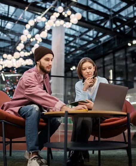 Two colleagues working on a laptop in a bright atrium