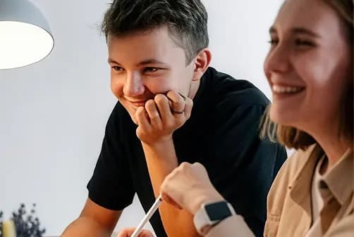 Two colleagues laughing together at a desk