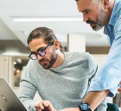 Two colleagues reviewing work on a laptop together