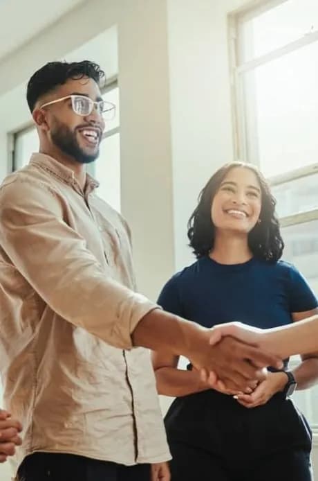 Two smiling colleagues shaking hands in an office