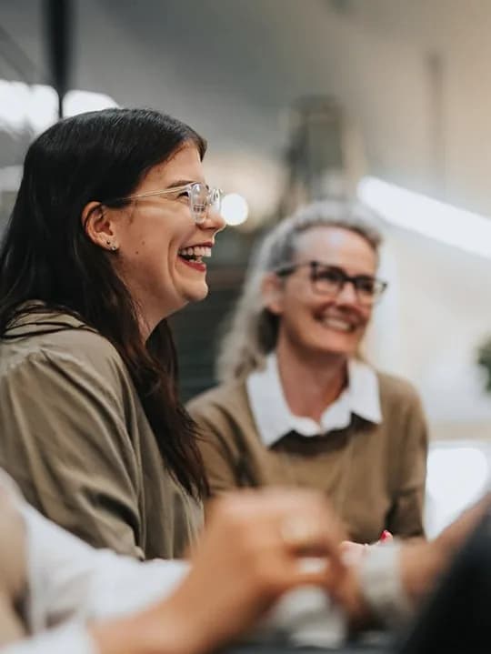 Two colleagues laughing together in a bright office