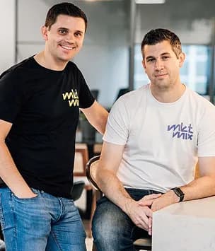 Two smiling colleagues posing together in an office