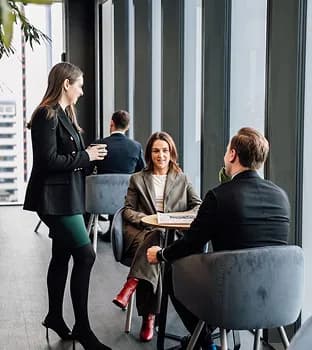 Colleagues chatting over coffee in a bright office lounge